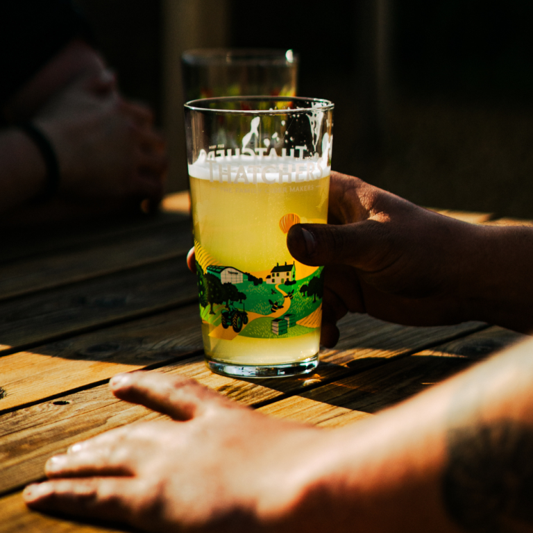 Hand holding a pint at The Baker’s Arms, perfect for celebrating finishing your pub desking shift.